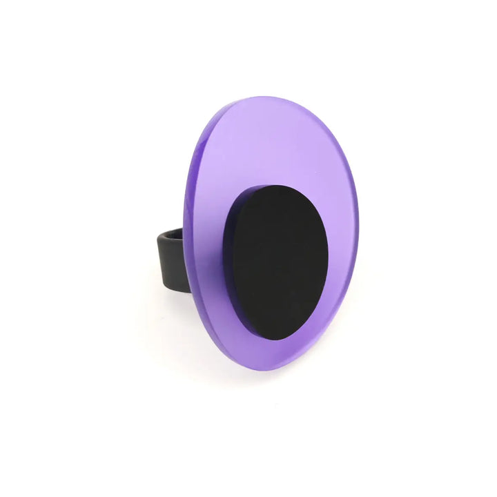 A purple round ring pop-style handheld mirror with a black grip attached to the back. The mirror, reminiscent of modern jewelry, has a circular shape and a handle that fits comfortably around a finger, similar to the Leya Ring by Alex + Svet, handcrafted in Paris.