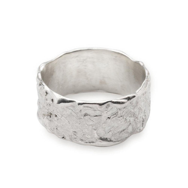 The Abbie Dixon Elements Ring Wide features a wide, textured band. The surface of this wide ring boasts an uneven, rough design, giving it a rugged, handcrafted appearance. Meanwhile, the inner side remains smooth and polished for comfortable wear.