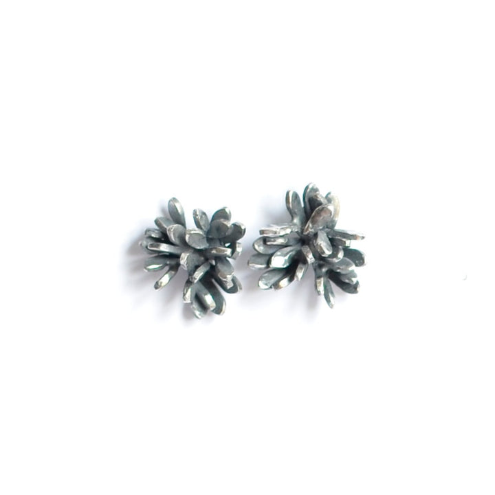 A pair of Folia Oxidised Silver Studs by Abbie Dixon designed to resemble small clusters of leaves or flowers, set against a plain white background. The intricate, sculptural form gives the earrings a delicate and unique appearance.