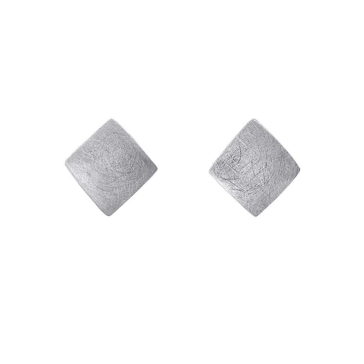 A pair of Deco Square Studs in sterling silver by Gallardo & Blaine Designs are displayed against a white background. The earrings feature a diamond shape with a textured, brushed metal finish that gives them a matte appearance.