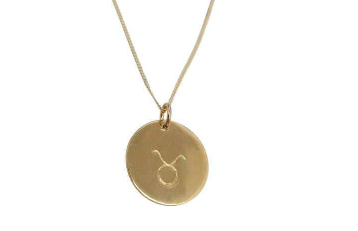 A Horoscope Large Disc Charm Gold by Personalised Charms with a thin chain. The round engraved disc charm proudly displays the astrological zodiac sign for Taurus.