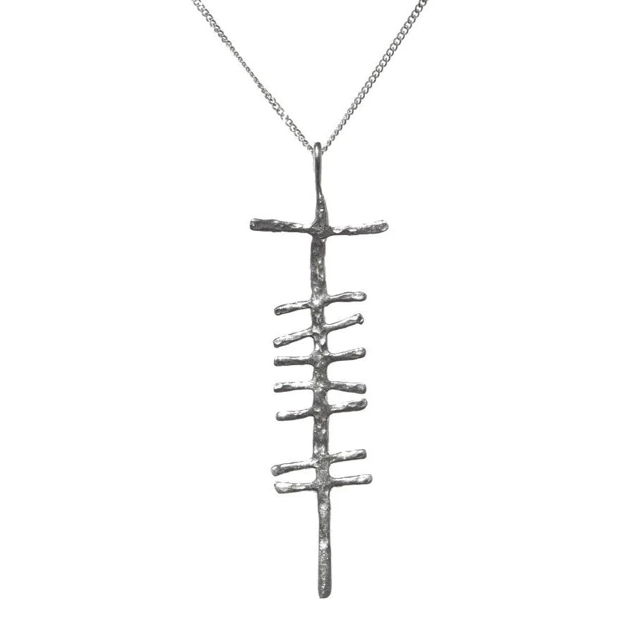 A Love (Grá) Large Rustic Pendant Silver by Ogham Treasure features a silver pendant with an abstract design, resembling a vertical rod with several short horizontal bars extending on both sides. The pendant, which evokes Ogham writing and bears a rough, textured finish, hangs from a delicate chain and exudes grá.