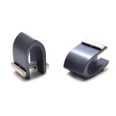 Two modern, sleek Ogive Wrap Around Cufflinks by Filip Vanas in a metallic blue finish are shown. Each cufflink has an arched design with a slot for holding pens. One is positioned upright, and the other is laid on its side, showcasing different angles of these innovative concepts.