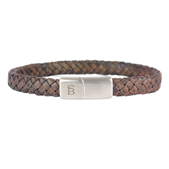 A Riley - Vintage Brown brown genuine braided leather bracelet by Steel and Barnett with a branded metal clasp. The clasp features a subtle engraved design on the surface, adding an elegant touch to the rugged texture of the leather. The bracelet exudes a stylish and sophisticated vibe.