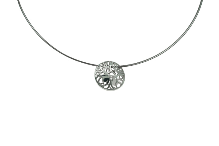 A silver necklace featuring a choker style with a central round pendant. The Líos Silver Pendant on Steel Cable by Miriam Wade displays an intricate, filigree tree design, reminiscent of the Irish countryside pendant, showcasing detailed and delicate branches and leaves. The background is plain white.