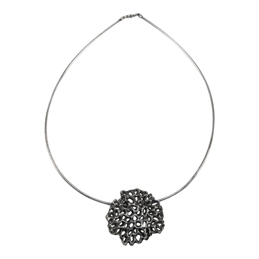 A modern sculptural jewelry piece, this silver necklace features a thin and flexible sterling silver omega chain with a large, intricate geometric pendant at its center. The Mythology Large Pendant Oxidised by Abbie Dixon has a dark, textured finish that resembles an organic, honeycomb-like pattern.