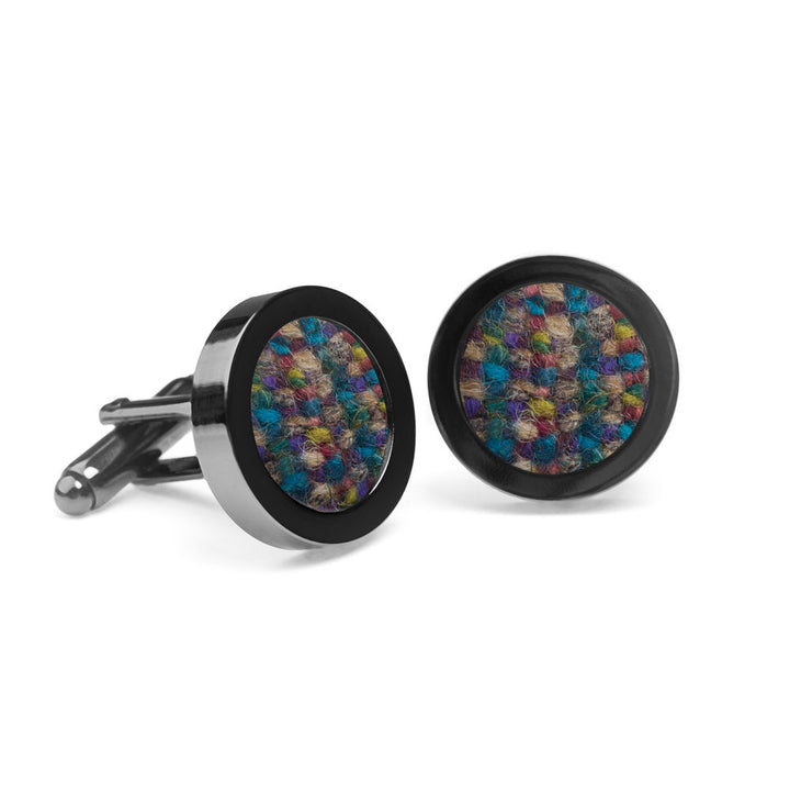 A pair of Motley Blends Tweed Cufflinks by Orwell & Browne featuring a multicolored woven pattern inside a polished black metal casing. The vibrant hues, crafted from Donegal tweed, include blue, purple, green, and brown. These sustainable cufflinks are placed on a white background.