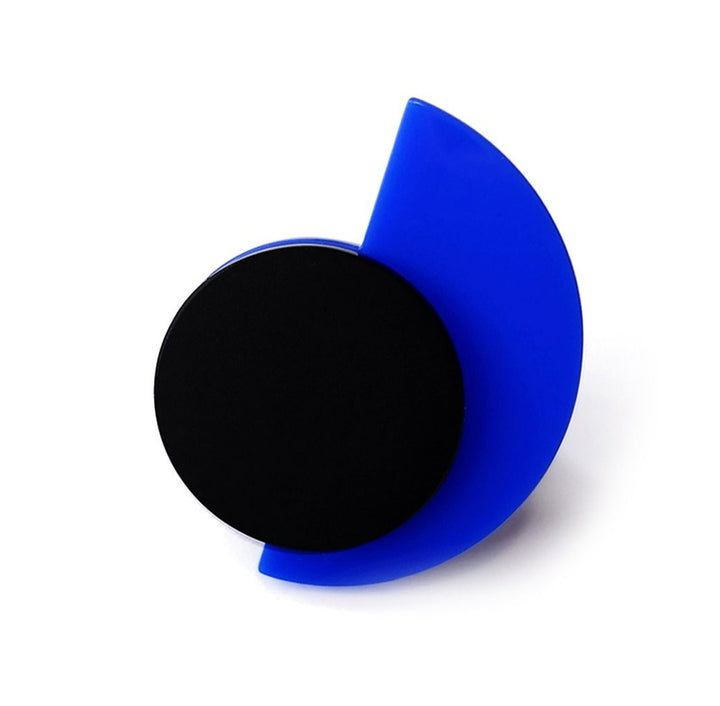 A geometric art piece, reminiscent of the Suzan Ring by Alex + Svet, features a solid black circle overlapping with a semi-translucent blue semicircle. The blue semicircle is positioned to the right, partially covering the black circle and creating a dynamic, minimalist composition.