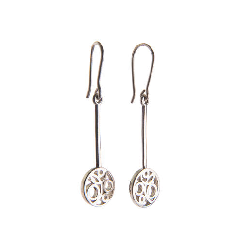 A pair of **Flow Long Drop Earrings Silver** by **Miriam Wade** with intricate circular designs at the bottom. Each earring has a long, thin handmade earring hook and stem leading to the circular element, which features a delicate, swirling pattern. The design is elegant and minimalistic.