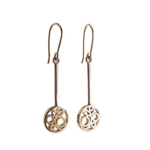 A pair of elegant yellow gold **Flow Long Drop Earrings Gold** with intricate circular filigree designs at the bottom. Each earring has handmade earring hooks that connect to a small round pendant featuring ornate cut-out patterns, crafted by **Miriam Wade**.