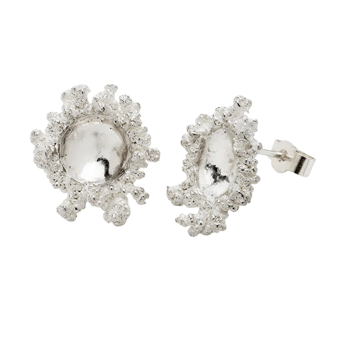 A pair of Spore Silver Studs by Abbie Dixon designed with a textured, coral-like outer rim surrounding a smooth, polished central dome. The earrings have butterfly backings and are placed on a plain white background.