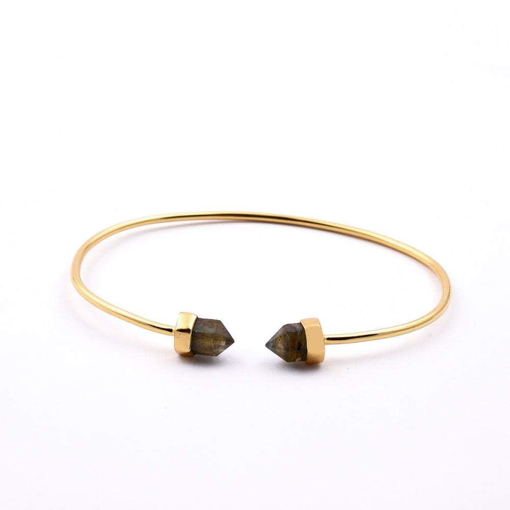 A Labradorite Gold Bracelet by Watermelon tropical, a minimalist gold vermeil bracelet with open ends, each featuring a small, pointed labradorite stone encased in a gold setting. This piece of handmade jewellery is displayed on a plain white background.