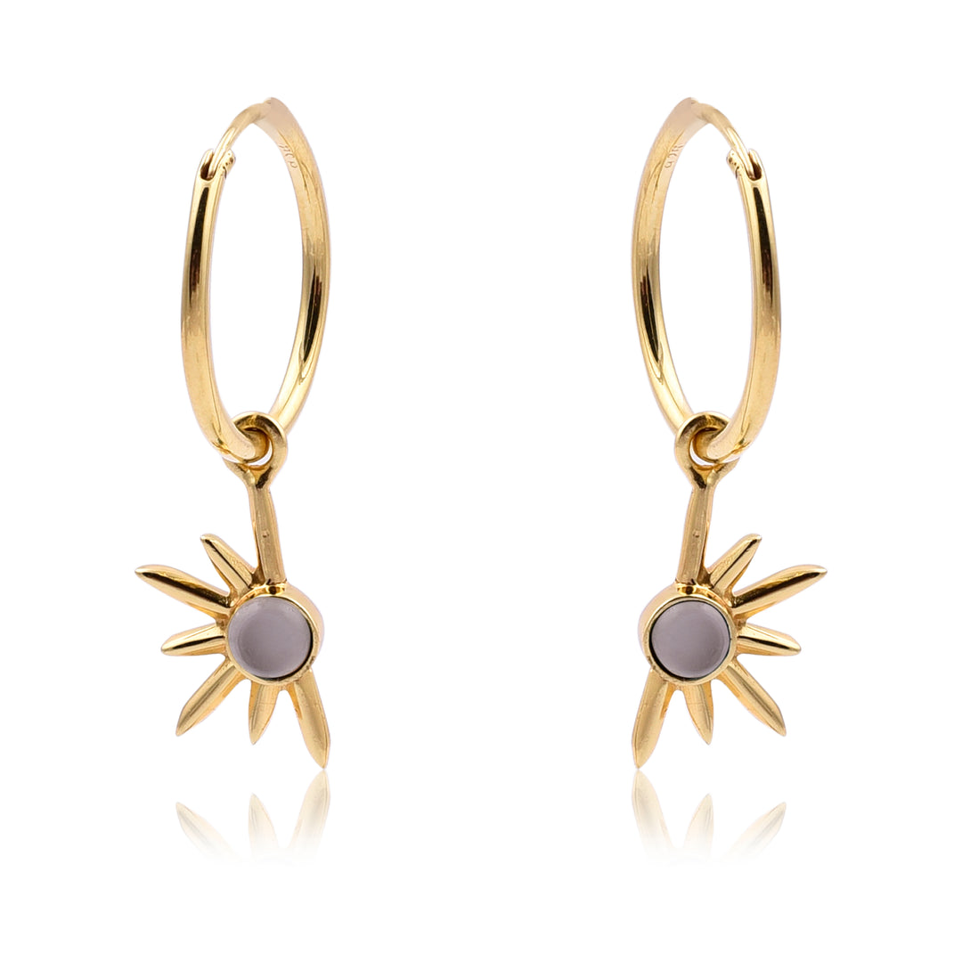 A pair of White Moonstone Half Star Gold Earrings from Watermelon tropical. The earrings feature a central white moonstone gem and radiating, pointed rays. The overall design is minimalistic and elegant, perfect for those who appreciate handmade jewellery.