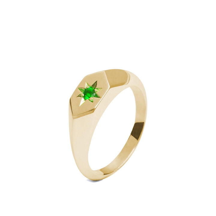 A handmade in Dublin, Starlight Emerald Birthstone 9ct Gold Signet Ring by Cosmic Boulevard featuring a hexagonal top with an engraved star pattern, housing the birthstone of May at the center. The band is smooth and polished, showcasing an elegant and minimalist design.