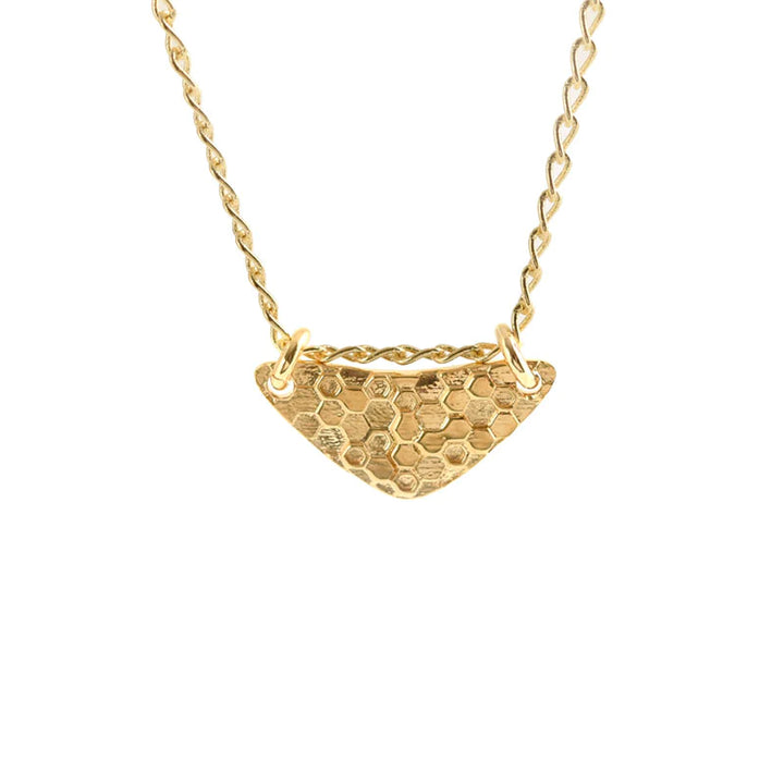 The Little Shield Necklace Gold by Andrea Mears Jewellery is a stunning gold plated sterling silver piece featuring a delicate chain and a textured, triangular pendant with a honeycomb pattern. The pendant is attached to the chain at two points, creating a balanced and elegant appearance. The necklace also boasts an adjustable length for versatility.