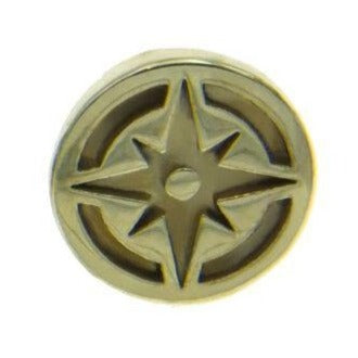 A brass-colored circular object with a cut-out design resembling a compass rose, perfect for those with an affinity for adventure and travel. The central hole is surrounded by eight triangular points, giving it a star-like appearance. The edges are smooth, and the overall design is simplistic yet elegant. This is the Compass Lapel Pin from Millett Wade.
