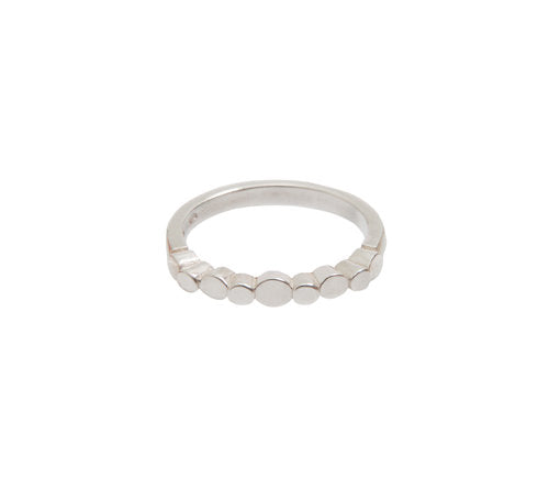 A minimalist sterling silver ring with a plain, polished band adorned with a row of small, circular, flat discs across the top, creating a modern and geometric design. This Irish hallmarked piece is displayed against a plain white background. Introducing the Flow Pebble Ring Silver from Miriam Wade.