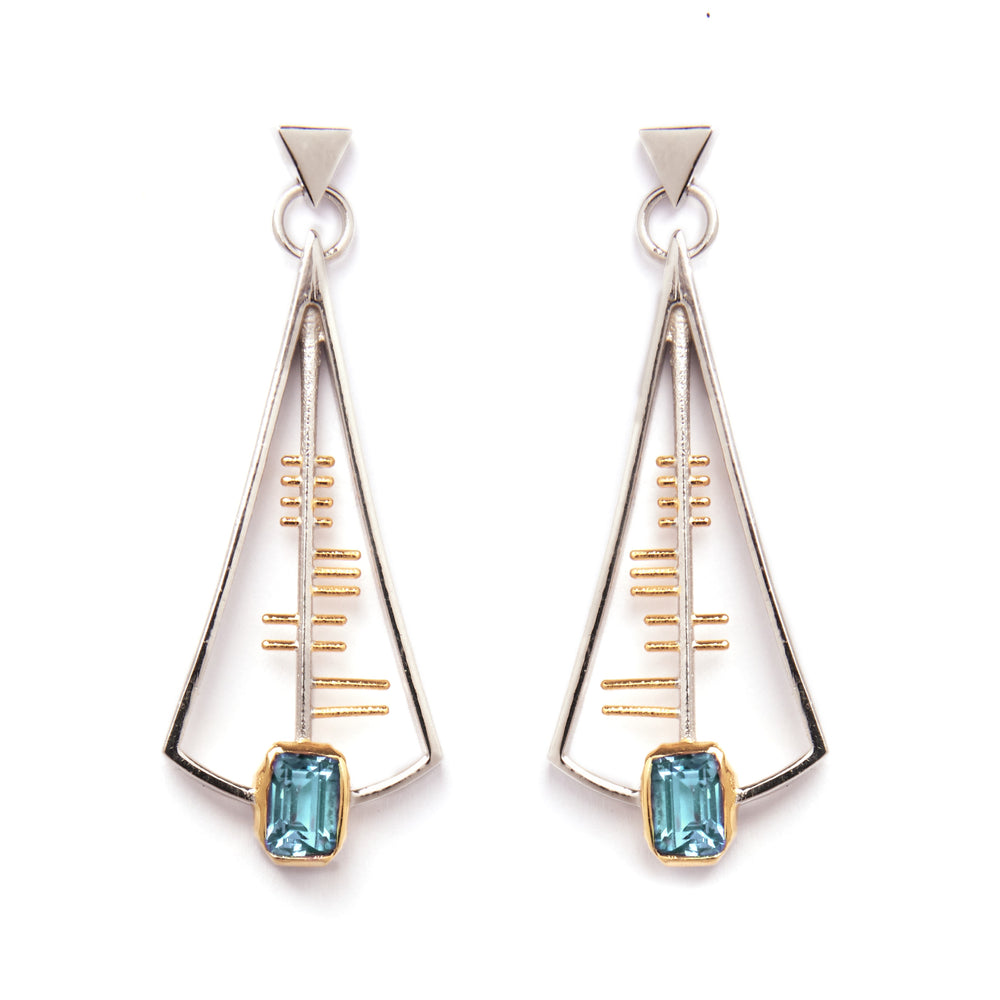 The Adeline Earrings by Gallardo & Blaine Designs feature a geometric, Art Deco-inspired design with a triangular sterling silver frame accented with gold and centered around a striking rectangular blue gemstone at the base. These earrings showcase a sleek, modern aesthetic with minimalist lines and shapes.