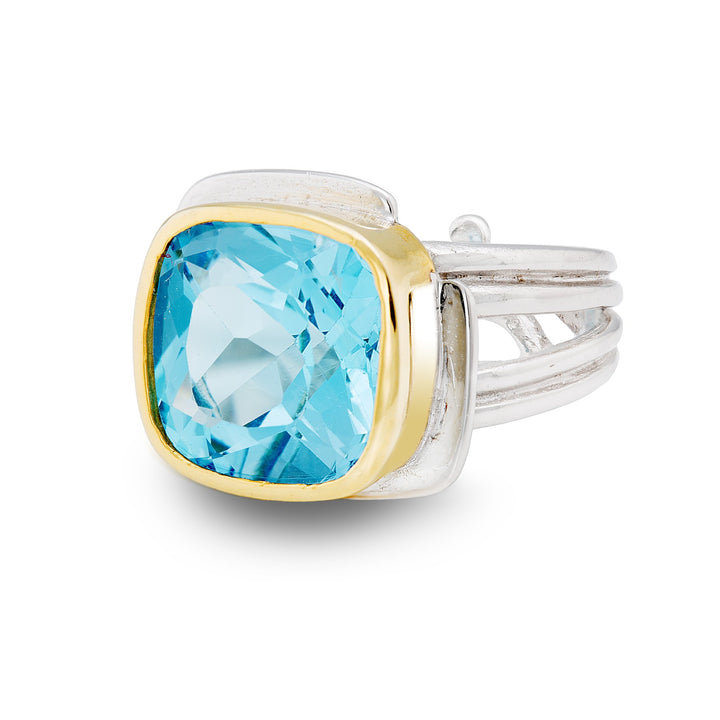 A silver ring with a large, square-cut blue gemstone set in a gold vermeil bezel. The Gallardo & Blaine Designs Art Deco Ring in Silver Gold & various gemstones, an exquisite Art Deco piece, features a striking multi-band design on the sides.