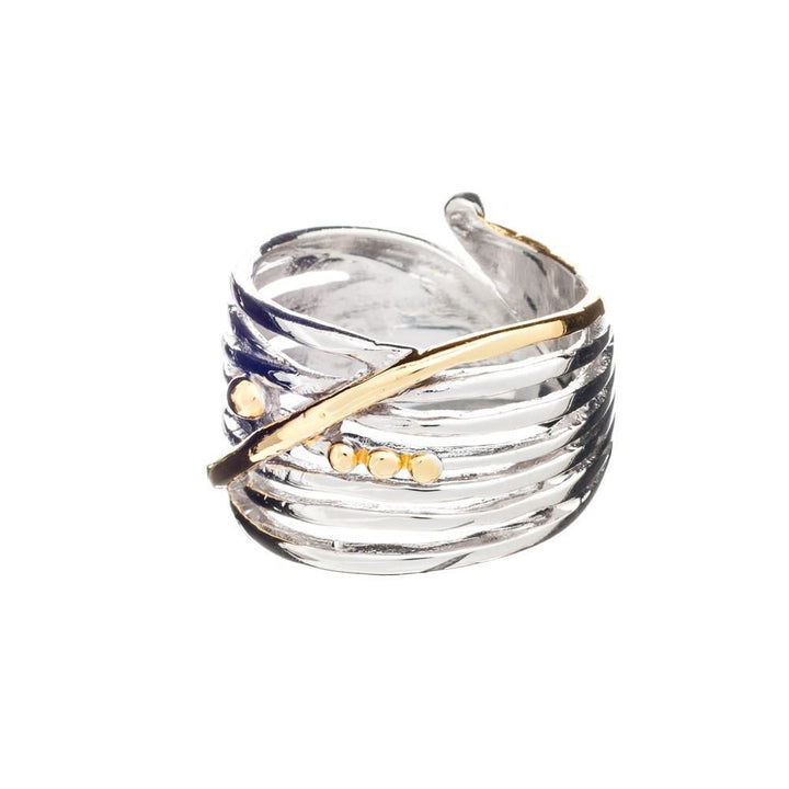 The Bamboo Ring in Sterling Silver & Gold Vermeil by Gallardo & Blaine Designs is a chunky adjustable ring crafted from sterling silver, featuring a layered, textured design with a diagonal gold vermeil band and several small gold dots. This stylish and contemporary piece blends metallic finishes to create an elegant and unique appearance.