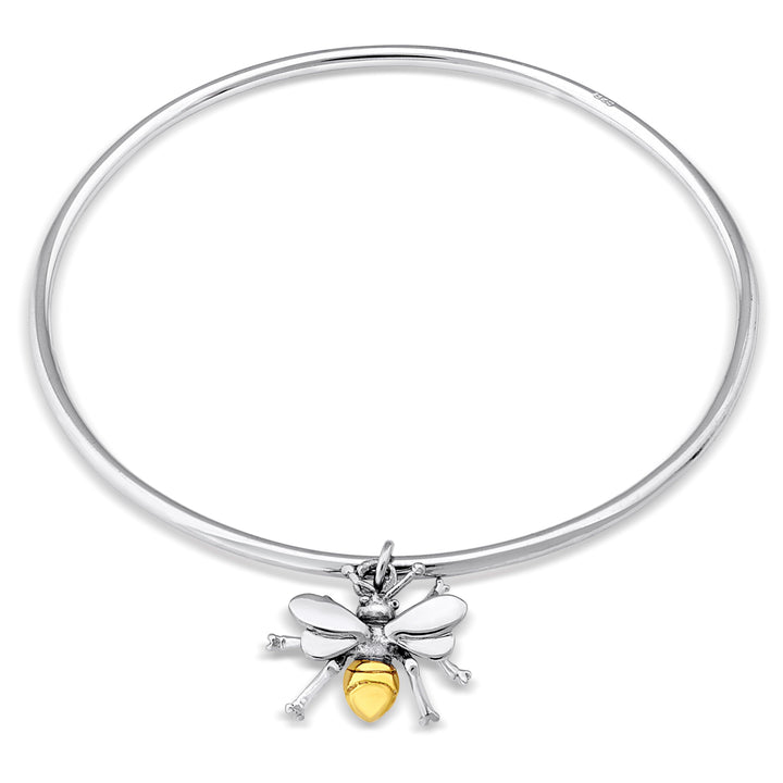 A Gallardo & Blaine Designs Wildlife Bee Bangle Silver & Gold featuring a charm in the shape of a honey bee. The bee charm has a yellow, enamel-coated body, silver wings and legs. The charm is attached to the bangle at the top, with the bee hanging down.