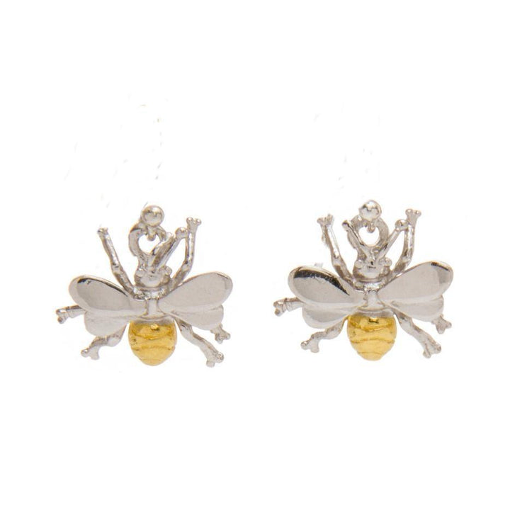 Introducing the Wildlife Bee Studs by Gallardo & Blaine Designs: a pair of silver and gold bee-shaped earrings. Crafted with sterling silver, these Bee studs feature detailed wings, a gold-toned abdomen, and six legs, closely resembling real bees. Each stunning piece is finished with gold plating and displayed on a white background.