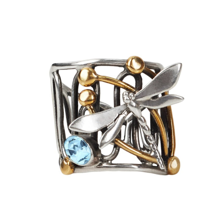 The Gallardo & Blaine Designs Dragonfly Ring features a sterling silver band highlighted by a dragonfly design with gold accents, a round blue gemstone, and an intricate openwork pattern blending smooth and textured elements for elegance.
