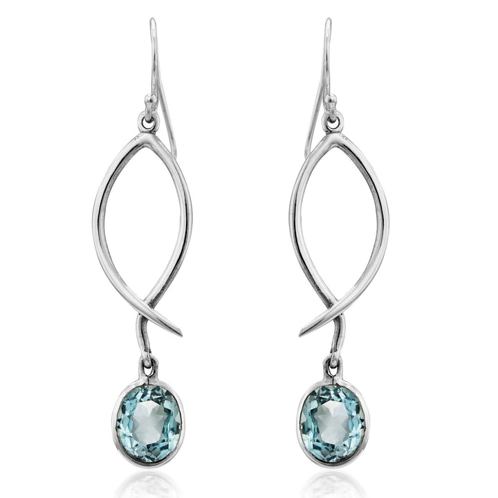 Graceful and elegant, the Lupin Earrings in various gemstones by Gallardo & Blaine Designs feature a twisting silver design with light blue, faceted oval gemstones at each twist's end. These versatile earrings add sparkling elegance to any outfit and make for stunning elegant drops.