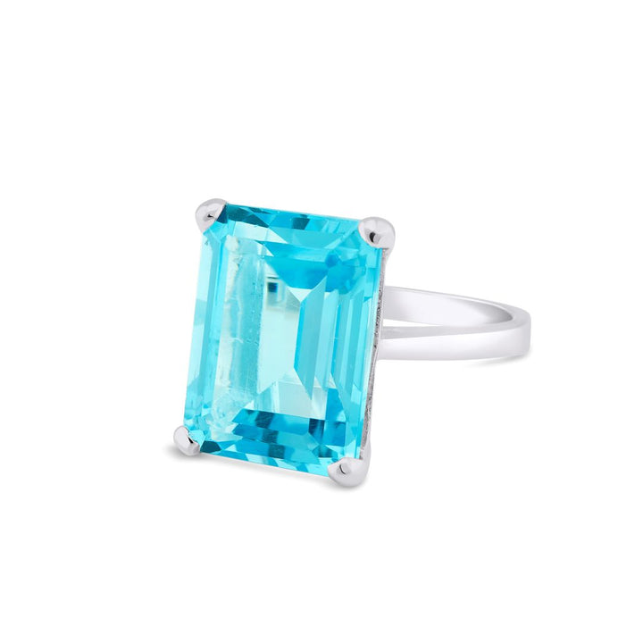 The Gallardo & Blaine Designs Stellar Ring in Hydro Blue Topaz features a large, rectangular-cut blue topaz held by four prongs. The gemstone is faceted, beautifully reflecting light, and giving the ring a luxurious and elegant appearance. Crafted from sterling silver, this piece exudes timeless sophistication.