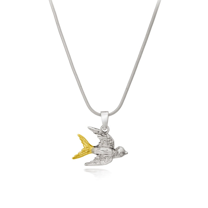 A sterling silver snake chain necklace featuring the Wildlife Pendant - Swallow With Chain by Gallardo & Blaine Designs. The bird has intricately detailed wings and body, while the 18ct gold plated tail feathers create a beautiful contrast against the sleek chain.