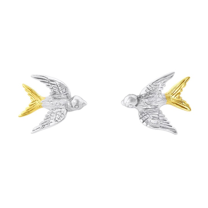 The Wildlife Swallow Studs from Gallardo & Blaine Designs, featuring detailed wings and feathers. The birds have silver bodies and heads with gold tails and wing tips. Both birds are positioned to face each other, creating a symmetrical and elegant design.