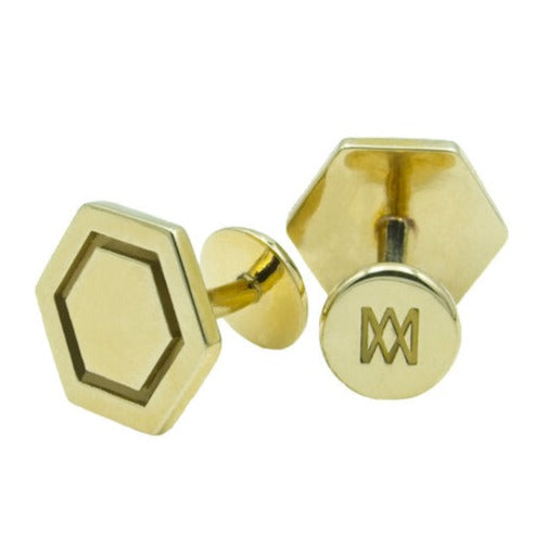 A pair of gold, hand-finished Hexagon Cufflinks with solid brass bases by Millett Wade. One cufflink boasts a plain hexagonal design, while the other features a pattern that resembles the letter "M" or a zigzag line.