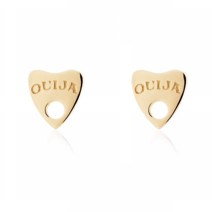 A pair of Ouija 9ct Gold Earrings by Cosmic Boulevard shaped like heart-shaped planchettes, commonly used with Ouija boards. Both earrings have the word "Ouija" engraved on them and feature a small circular cutout at the base, embodying mysticism and spirituality. The background is white.
