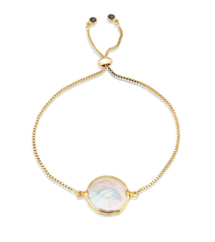 A delicate gold plated brass chain bracelet featuring a central large, irregularly shaped freshwater pearl. The Perle Bracelet by Aria V includes an adjustable sliding clasp and two small end beads for secure fastening. The pearl's unique luster adds an elegant touch to the piece.