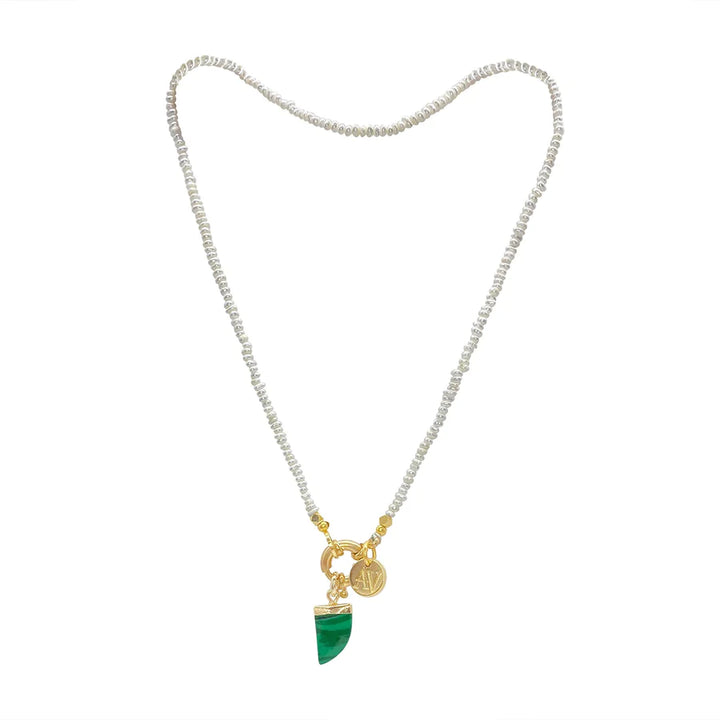 A choker-style necklace featuring small, round, white beads strung together. It has a gold clasp at the center, from which a Malachite spear stone pendant and a circular gold charm with an engraved design hang. The green Malachite stone is shaped like a pointed talon. This is the Siren Malachite Choker/Bracelet from Aria V.