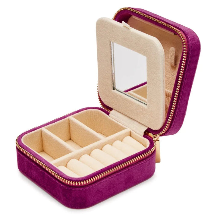 A small, open SoCases Luxurious Wildberry Velvet Travel Jewellery Box with a zipper. The interior is lined with beige fabric and features multiple compartments: three sections on the left for various jewelry pieces and a slotted section on the right for rings. A mirror is attached to the lid, ideal for travel jewellery storage.